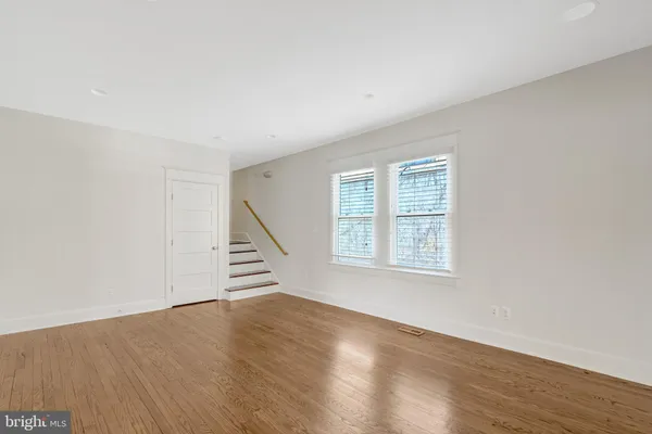a view of an empty room with wooden floor and stairs