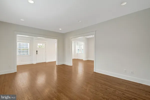 a view of an empty room with wooden floor and windows