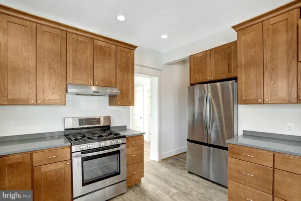 a kitchen with stainless steel appliances granite countertop a refrigerator a sink and white cabinets with wooden floor