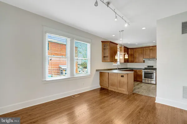 a kitchen with granite countertop a stove a sink and white cabinets with wooden floor