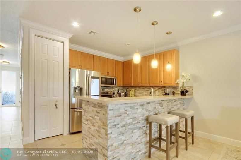 a kitchen with kitchen island granite countertop a sink cabinets and refrigerator