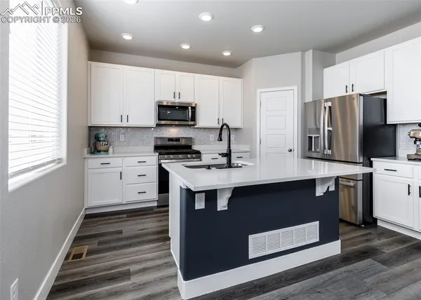 a kitchen with stainless steel appliances a sink a stove a refrigerator cabinets and a window