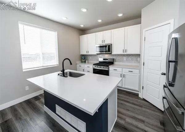 a kitchen with white cabinets and black appliances