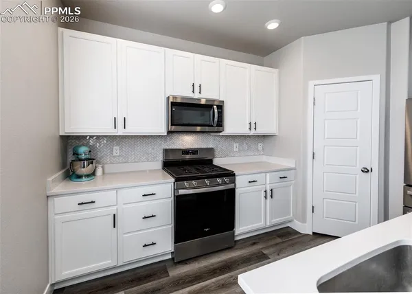 a kitchen with stainless steel appliances granite countertop a stove a microwave and a white cabinets