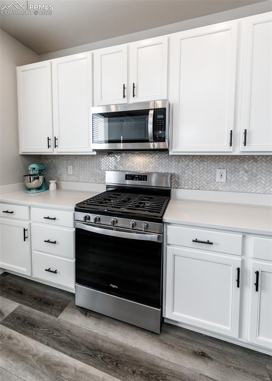 12653 Granite Ridge Drive Peyton, CO 80831 - Photo 16 of 50 a kitchen with stainless steel appliances granite countertop a stove a microwave and a white cabinets