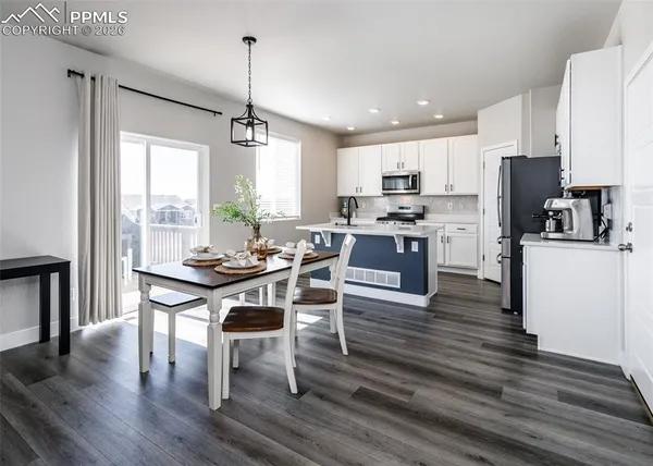 a kitchen with a table chairs refrigerator and microwave