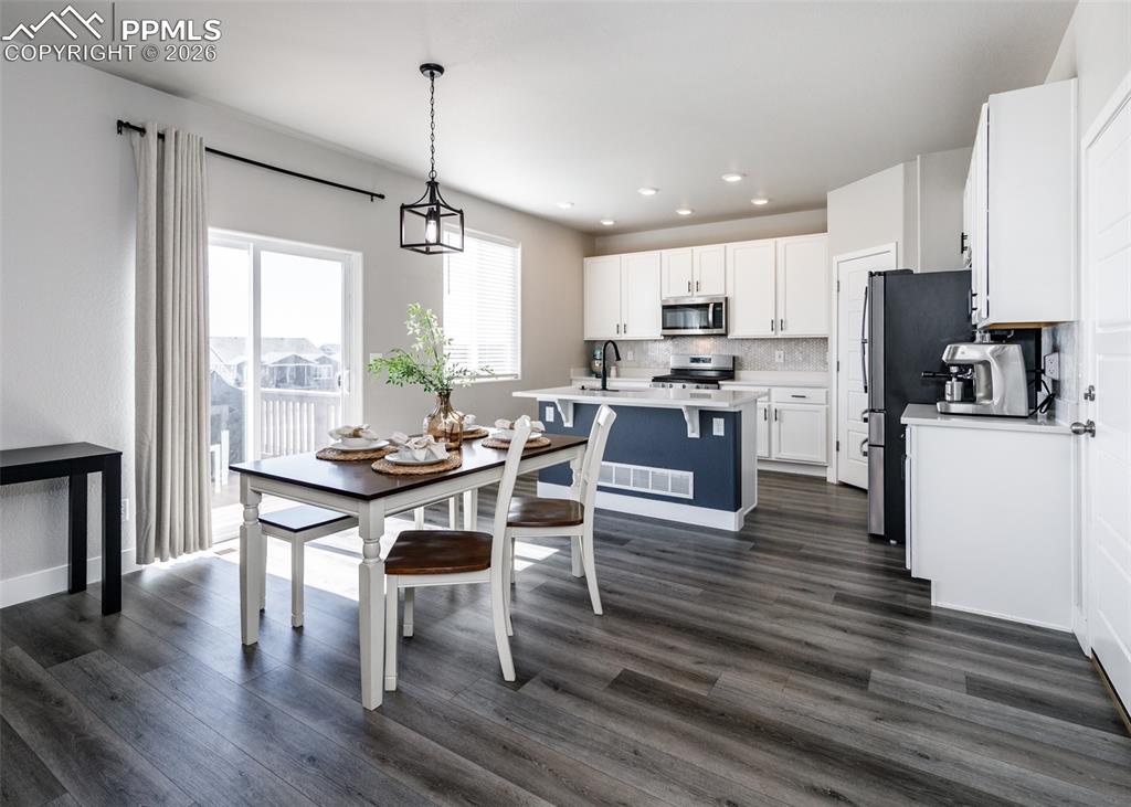 12653 Granite Ridge Drive Peyton, CO 80831 - Photo 10 of 50 a kitchen with stainless steel appliances a dining table chairs stove refrigerator and cabinets