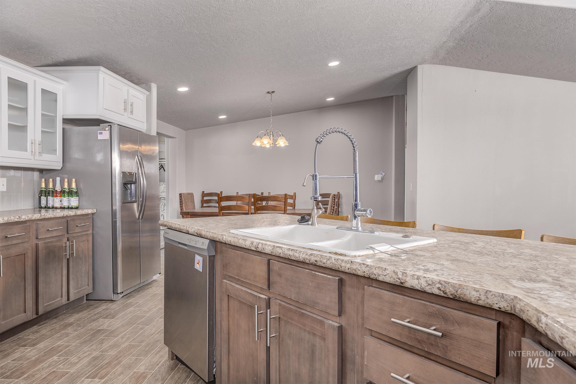 1587 Gentry Lane Weiser, ID 83672 - Photo 13 of 41 Kitchen with a chandelier, glass insert cabinets, appliances with stainless steel finishes, a textured ceiling, and decorative light fixtures
