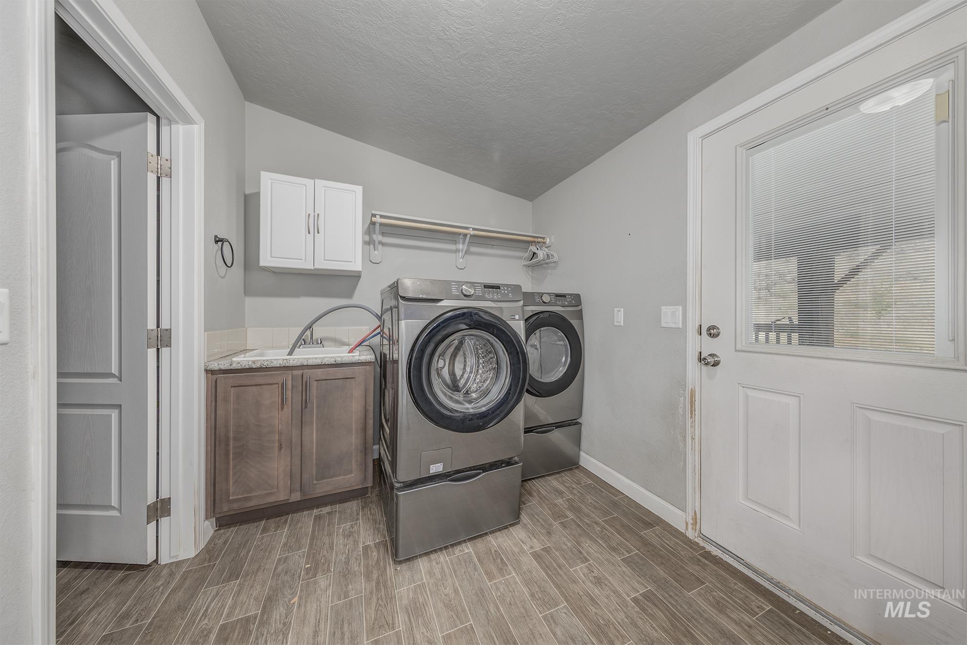 1587 Gentry Lane Weiser, ID 83672 - Photo 14 of 41 Laundry room with a textured ceiling, wood tiled floors, cabinet space, and washing machine and dryer