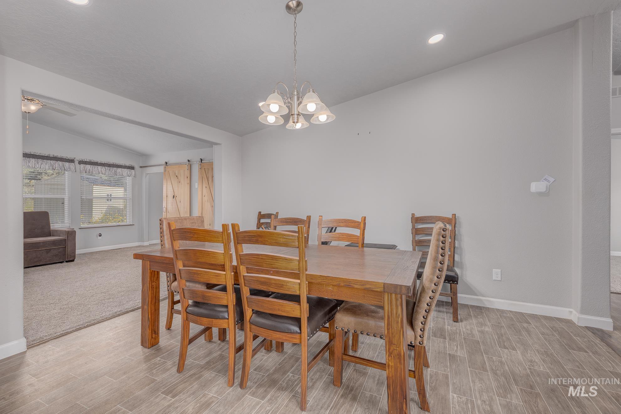 1587 Gentry Lane Weiser, ID 83672 - Photo 16 of 41 Dining area featuring vaulted ceiling, wood finish floors, a chandelier, and recessed lighting