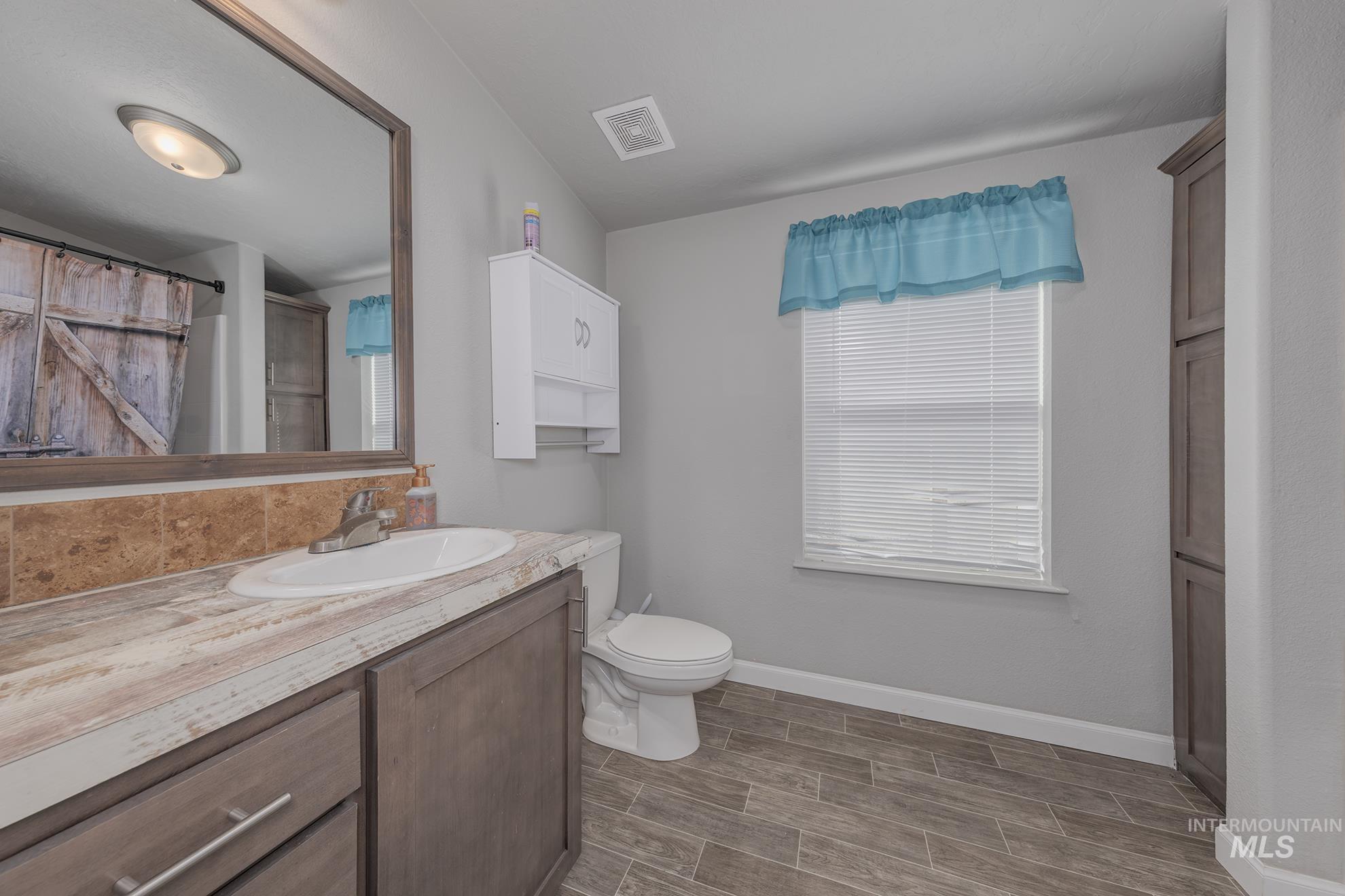 1587 Gentry Lane Weiser, ID 83672 - Photo 22 of 41 Full bathroom featuring vanity, wood finish floors, and a shower with shower curtain