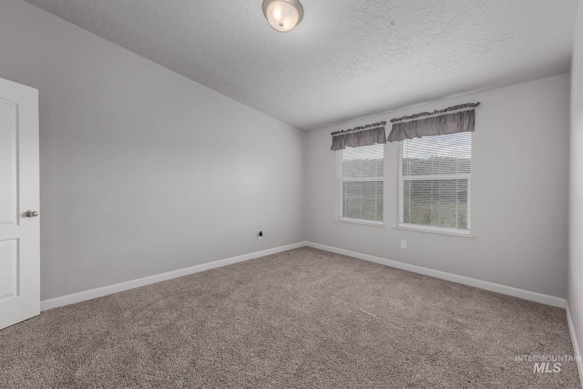 1587 Gentry Lane Weiser, ID 83672 - Photo 24 of 41 Unfurnished room with carpet, a textured ceiling, and vaulted ceiling