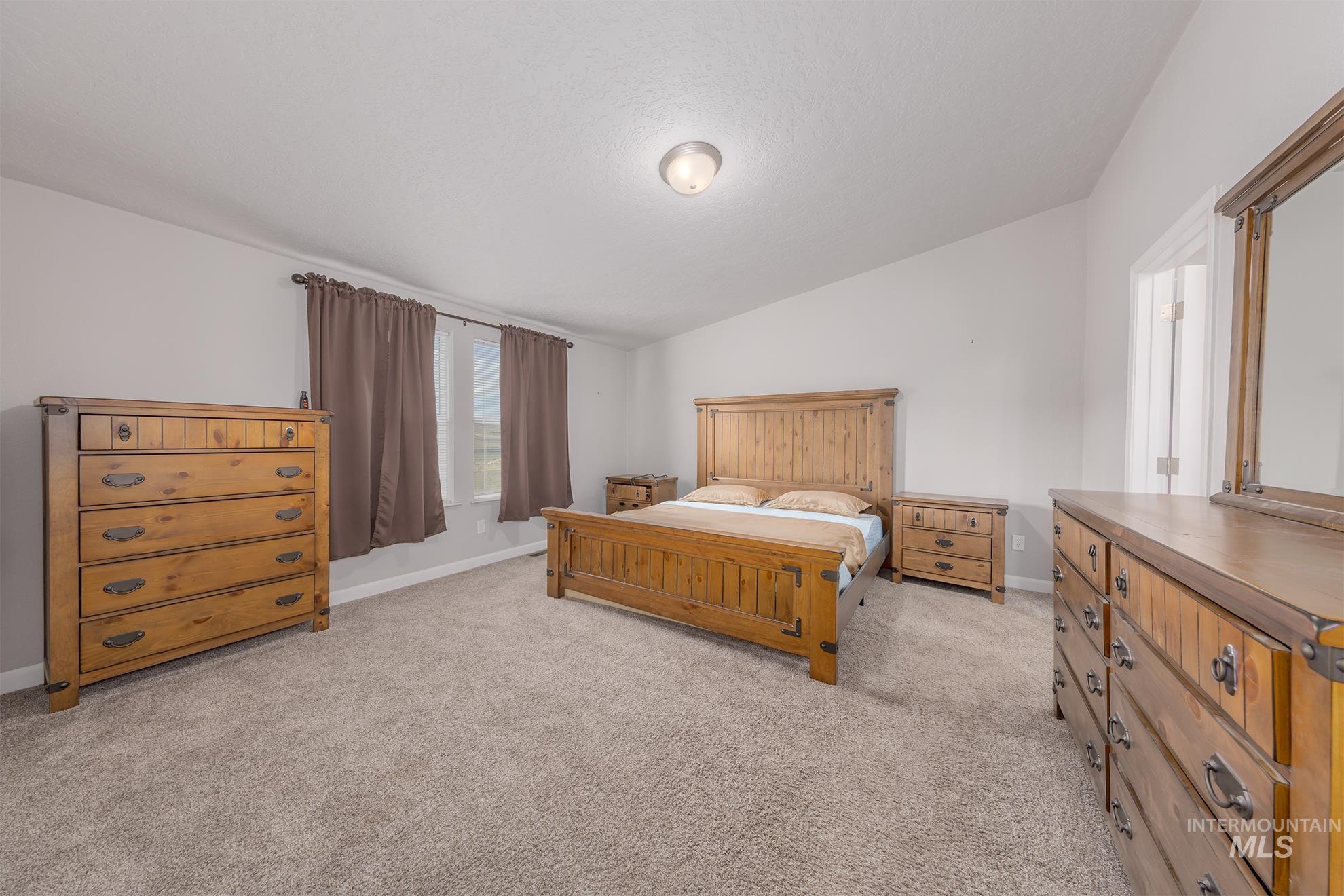 1587 Gentry Lane Weiser, ID 83672 - Photo 27 of 41 Bedroom with lofted ceiling, light colored carpet, and a textured ceiling