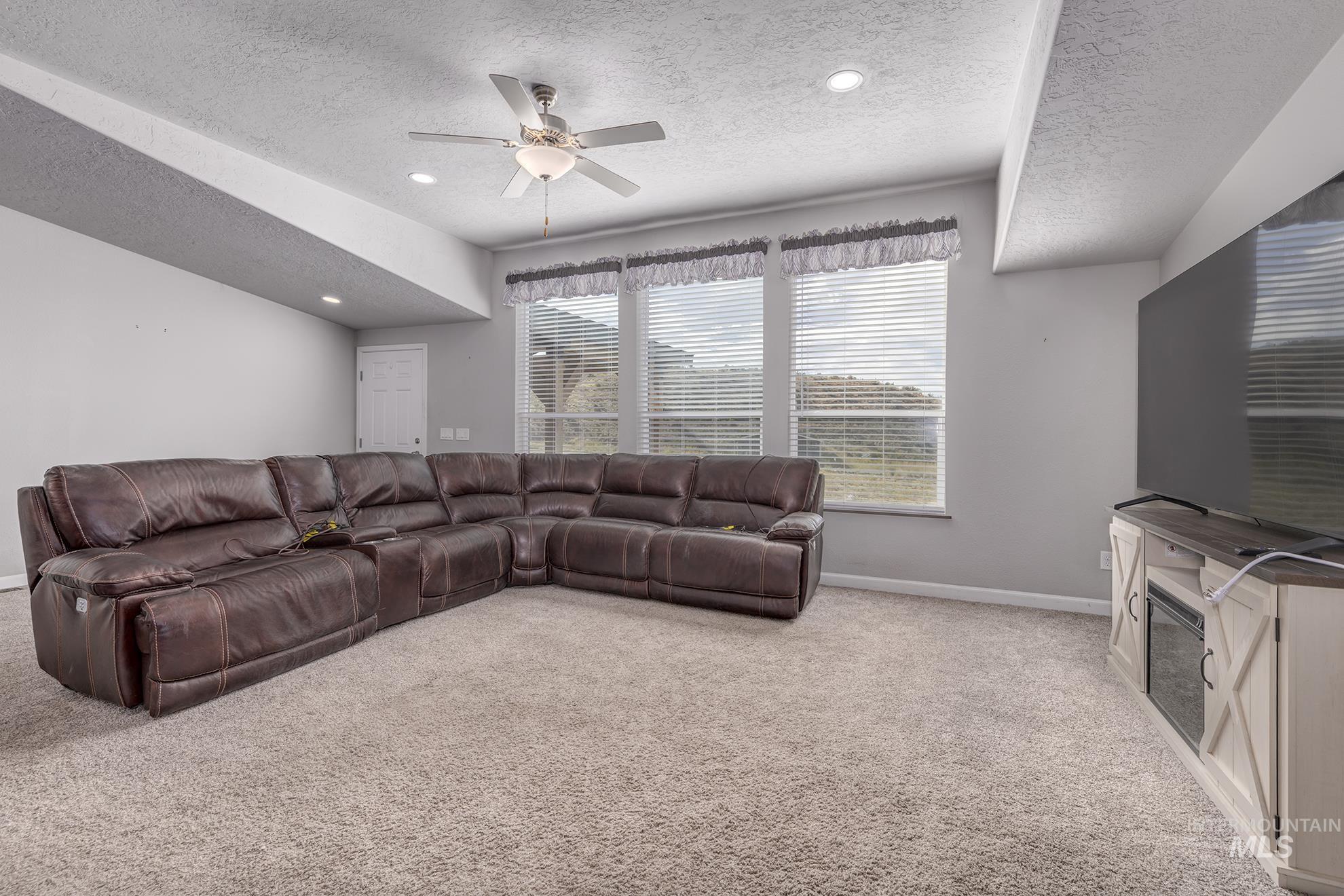 1587 Gentry Lane Weiser, ID 83672 - Photo 7 of 41 Living room with light carpet, a textured ceiling, a ceiling fan, and recessed lighting