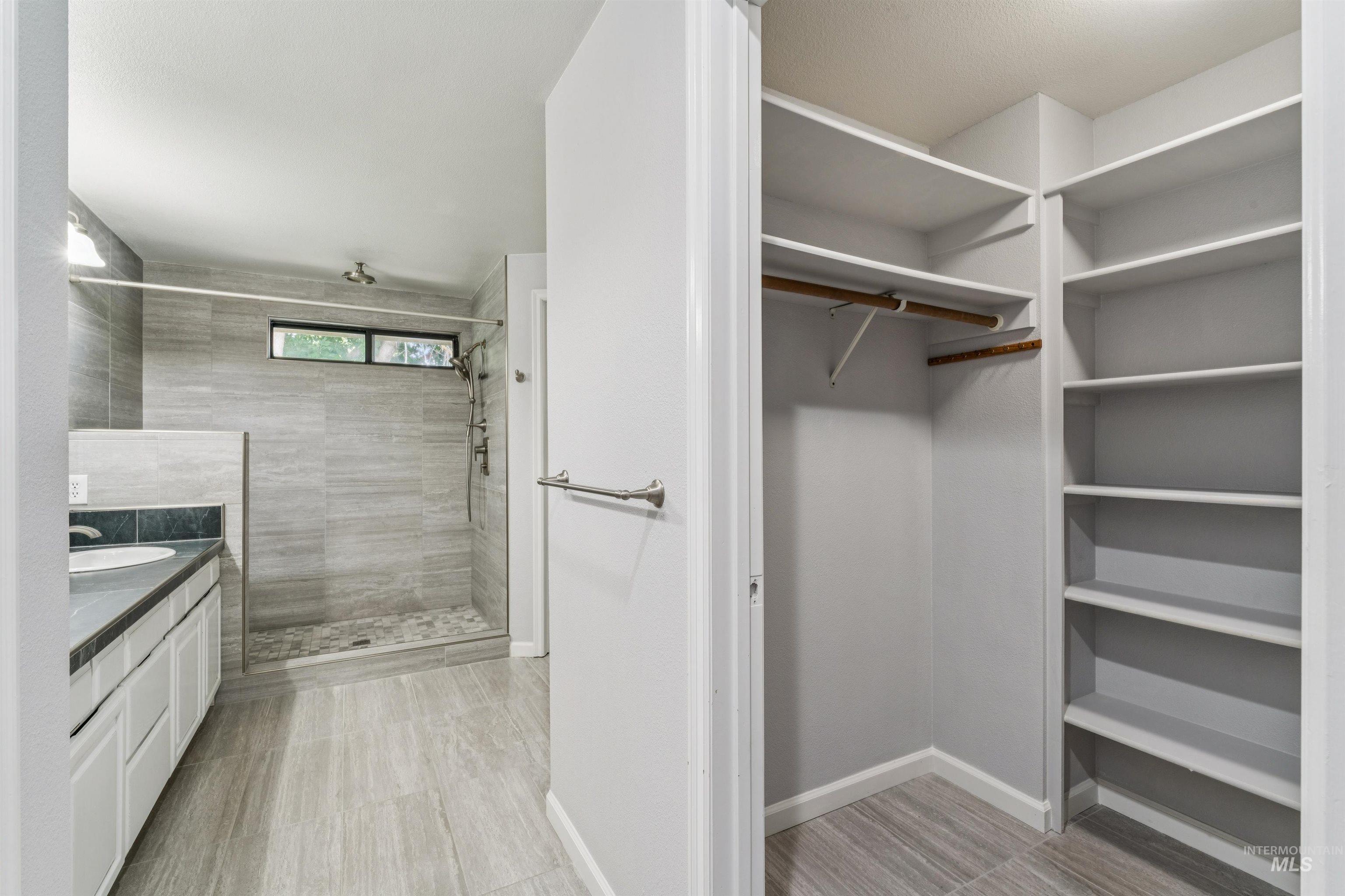 9831 West Ripley Street Boise, ID 83704 - Photo 22 of 47 Spacious bathroom featuring a dual vanity with undermount sinks, dark stone-finish countertops, and white cabinetry