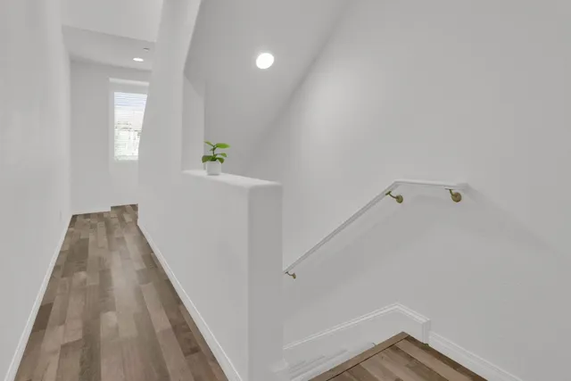a view of a hallway with wooden floor and a bathroom