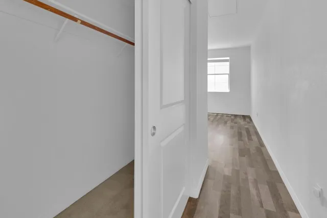 a view of a hallway with wooden floor and a bathroom