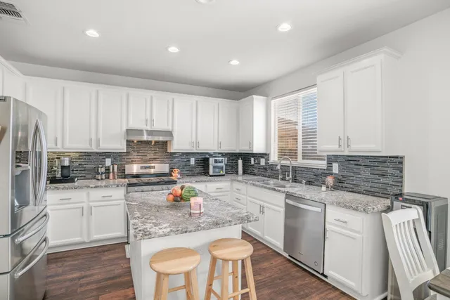 a kitchen with white cabinets and appliances