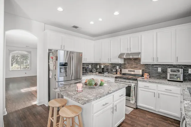 a kitchen with kitchen island granite countertop a stove sink and refrigerator