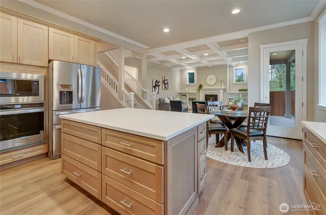 a living room with stainless steel appliances kitchen island granite countertop a table chairs and a view of living room