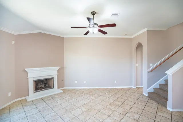 a view of an empty room with a fireplace and a ceiling fan