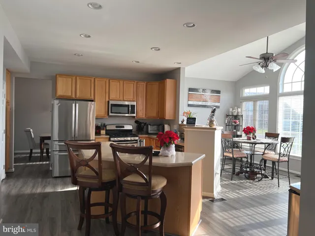 a kitchen with stainless steel appliances a table chairs refrigerator and microwave