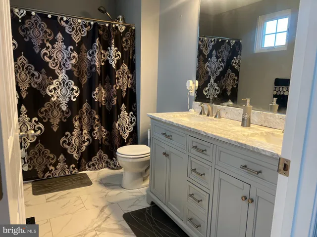 a bathroom with a granite countertop toilet and a shower curtain