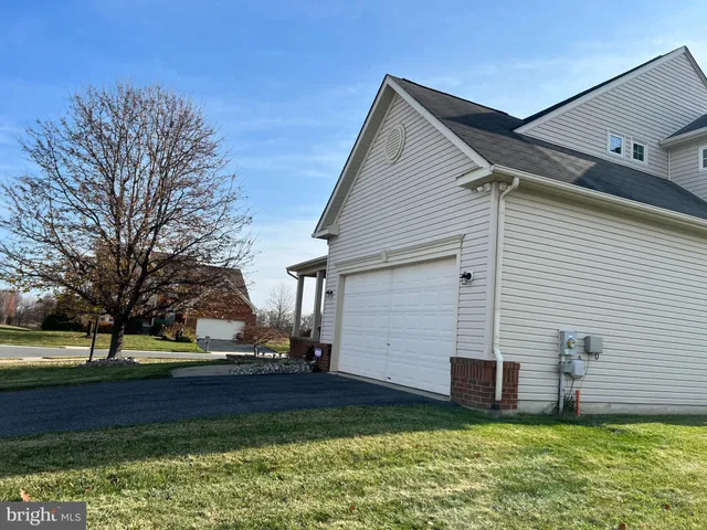a view of a white house next to a yard with a large tree