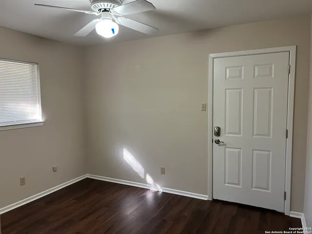 an empty room with wooden floor closet and windows