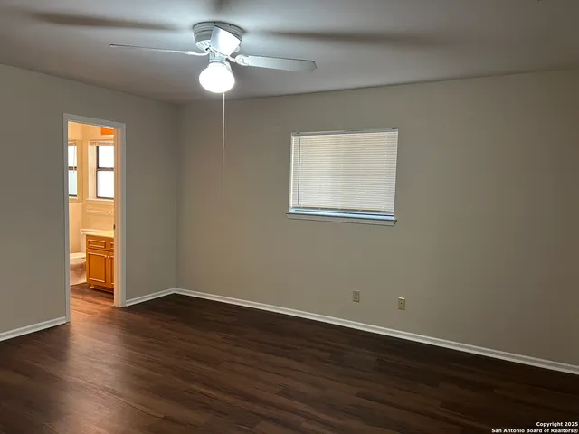a big room with wooden floor a chandelier fan and windows