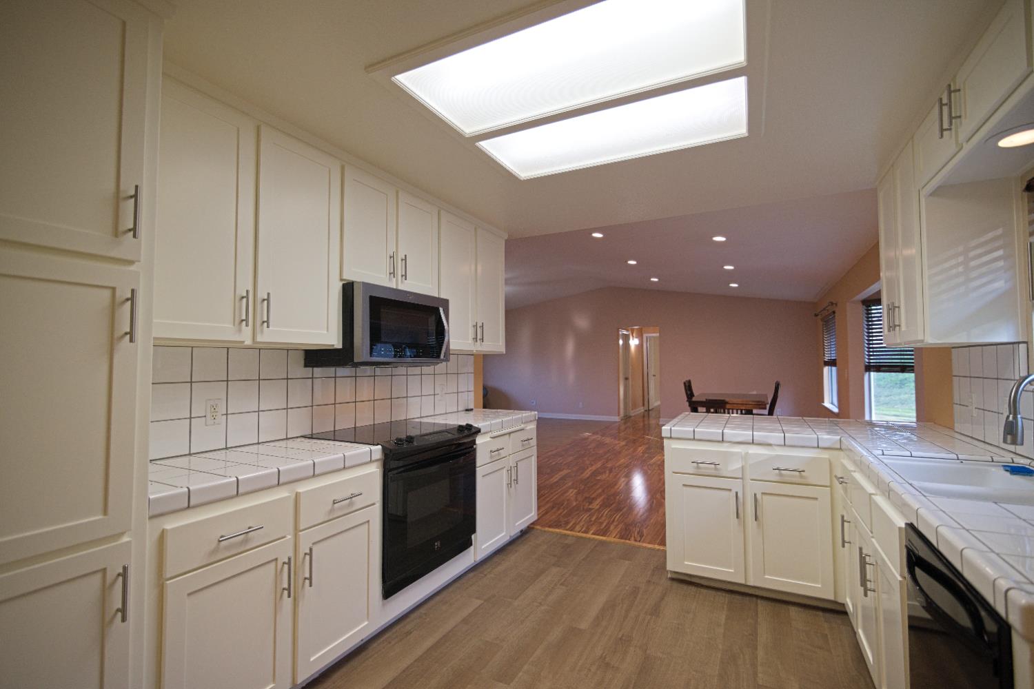 33072 Black Mountain Road Tollhouse, CA 93667 - Photo 14 of 45 a kitchen with a sink dishwasher stove and white cabinets with wooden floor