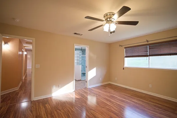 a view of empty room with wooden floor and fan