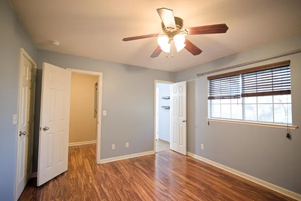 a view of an empty room with wooden floor and a window