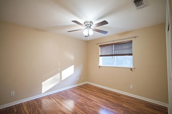 a view of an empty room with window and wooden floor
