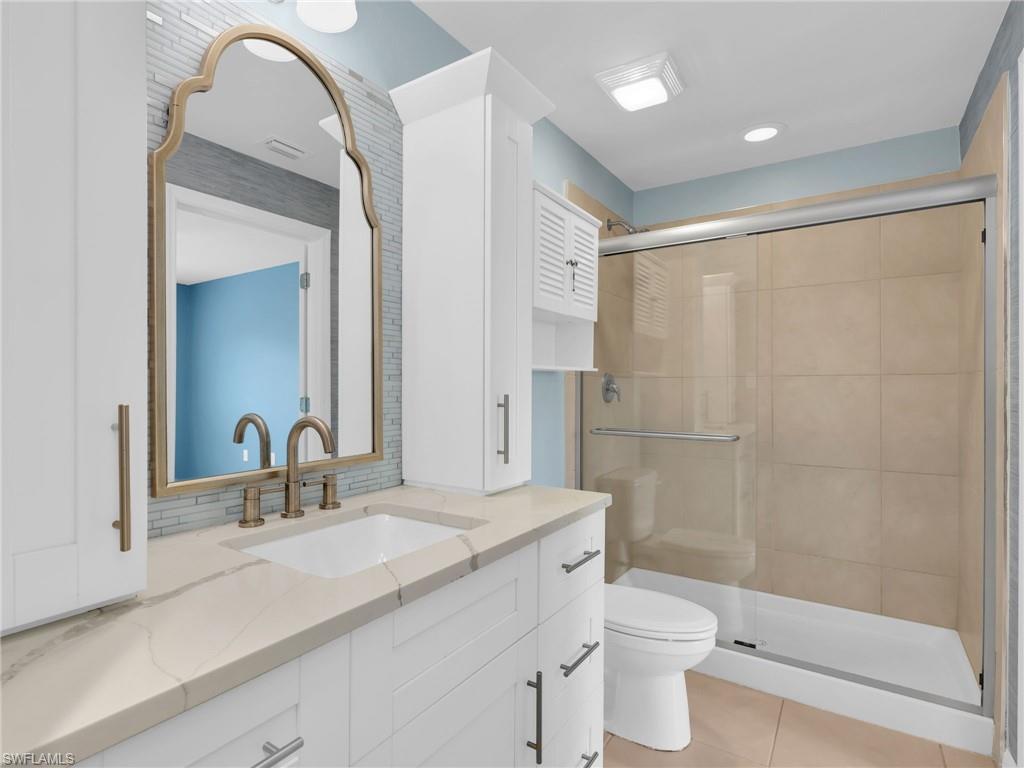 731 Hadley Place West Naples, FL 34104 - Photo 23 of 30 Primary En-Suite Bathroom With Renovated White Shaker Cabinetry With Drawers and Cabinet Towers, Added Backsplash, and Tiled Shower With Glass Enclosure