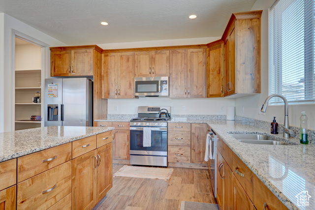 1329 Paseos Street Washington, UT 84780 - Photo 7 of 35 Kitchen featuring appliances with stainless steel finishes, light wood-type flooring, light stone counters, brown cabinetry, and recessed lighting