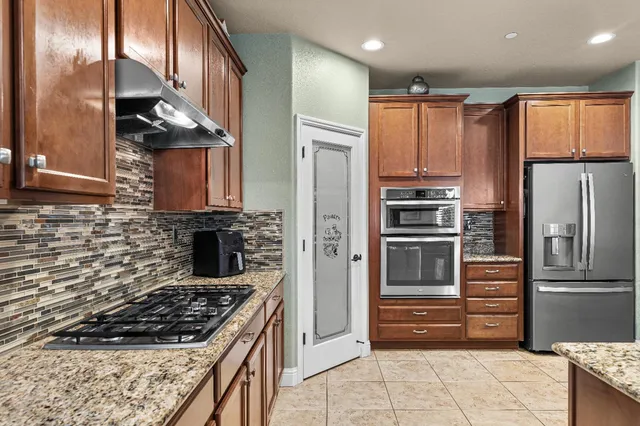 a kitchen with stainless steel appliances granite countertop a refrigerator and a sink