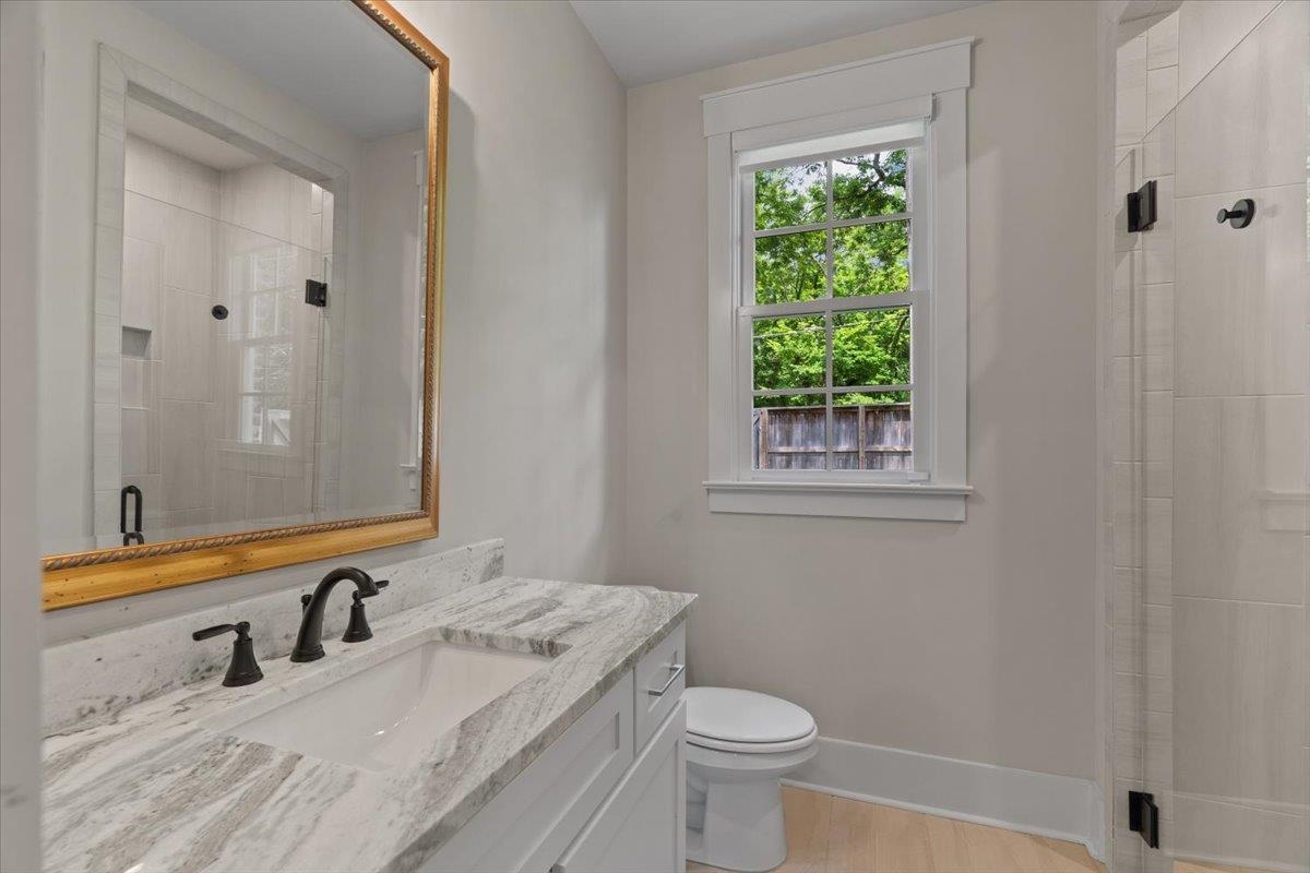 240 Burrows Road Collierville, TN 38017 - Photo 19 of 37 Bathroom vanity featuring a stone countertop with an integrated sink, matte black faucet, and a decorative framed mirror