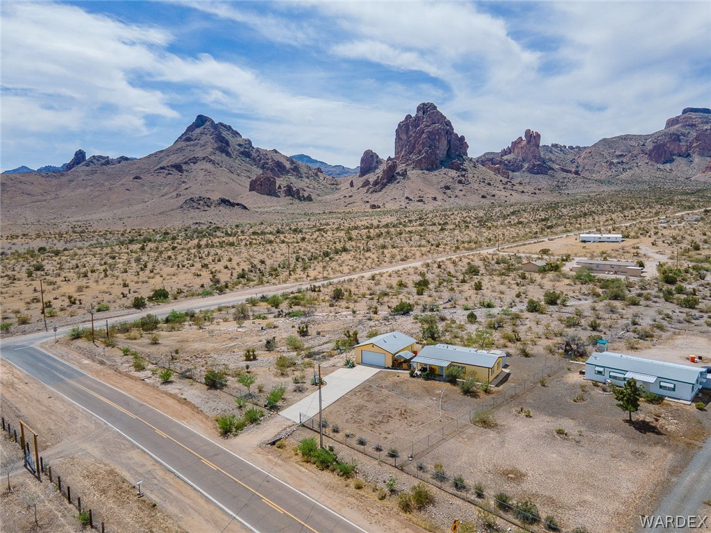 2465 Egar Road Golden Valley, AZ 86413 - Photo 91 of 98 Aerial view showcasing the property with a yellow exterior and a detached garage, set against a backdrop of prominent rock formations