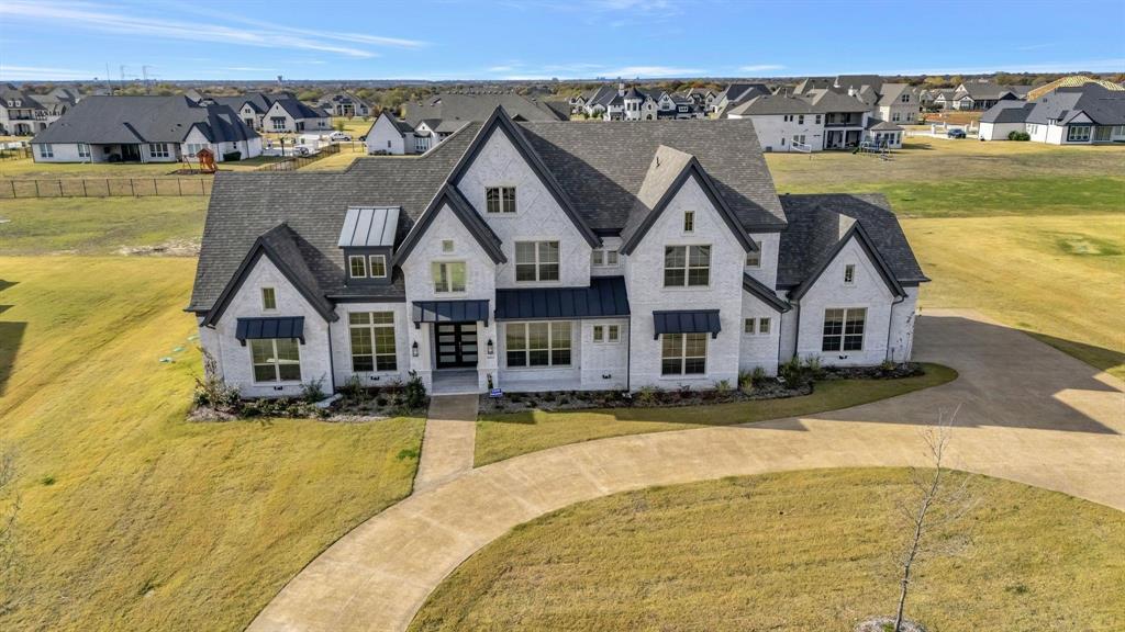 View of front of house with a residential view, curved driveway, a standing seam roof, and a front lawn