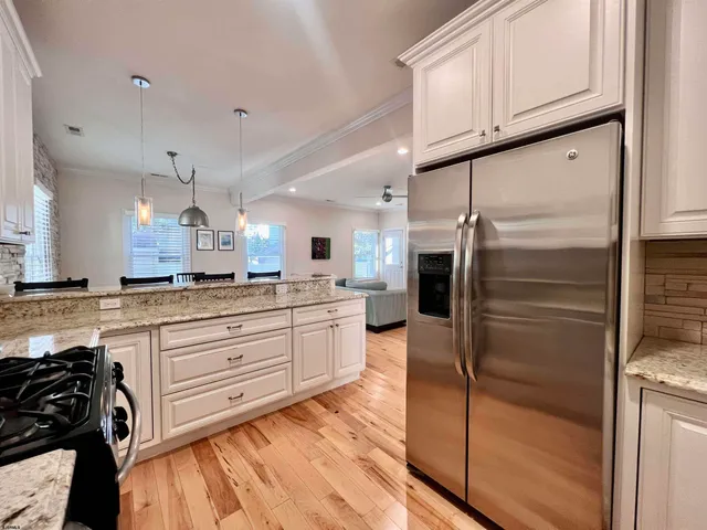 a kitchen with stainless steel appliances granite countertop a refrigerator a stove and a sink with wooden floor