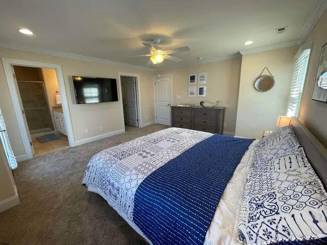 a spacious bedroom with a large bed a flat tv screen and dresser