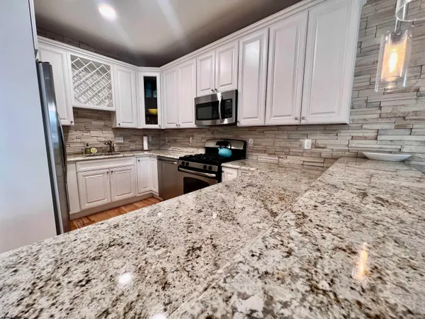 a kitchen with stainless steel appliances granite countertop a stove a sink and white cabinets