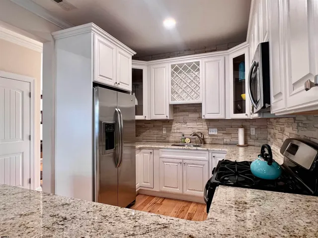 a kitchen with stainless steel appliances kitchen island granite countertop a refrigerator and a stove top oven