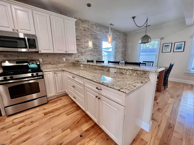 a kitchen with stainless steel appliances granite countertop a stove a sink and white cabinets
