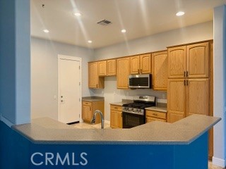 10495 Bridge Haven Road Apple Valley, CA 92308 - Photo 4 of 19 a kitchen with kitchen island granite countertop a stove top oven a sink a refrigerator white cabinets and wooden floor