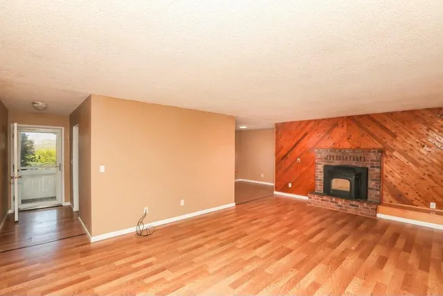 a living room with stainless steel appliances kitchen island granite countertop a sink and wooden floor
