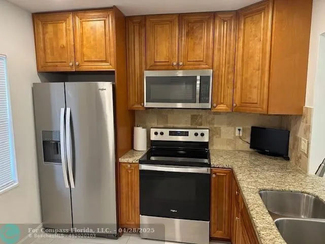 a kitchen with granite countertop a refrigerator stove and microwave