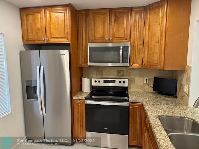 7605 Northwest 5th Court, Unit 208 Margate, FL 33063 - Photo 2 of 25 a kitchen with granite countertop a refrigerator stove and microwave
