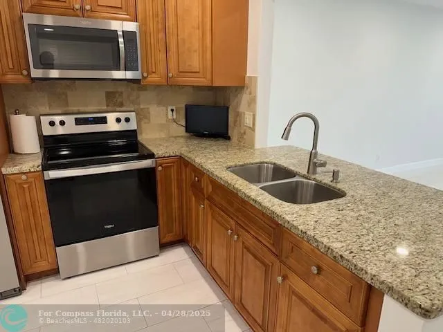 a kitchen with stainless steel appliances granite countertop a sink stove and microwave